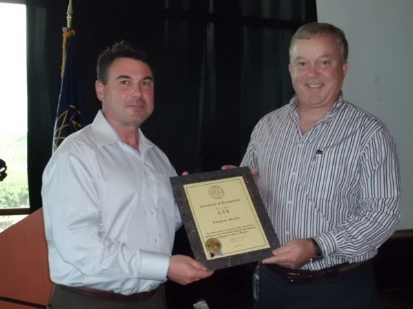 Robert Haulbrook, president and chief executive officer of GTA TeleGuam, accepts a corporate membership plaque from Matt Hempel, chapter vice president for programs.