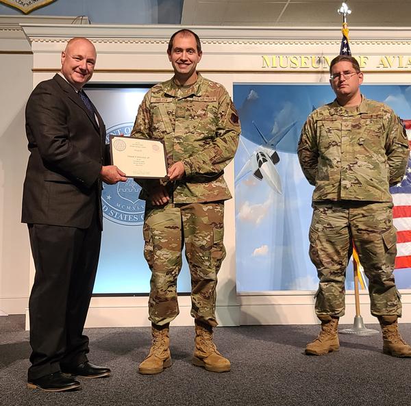 In May, Col. Janicki presents a coin and certificate for April Emerging Leader Airman 1st Class Frank P. DioLosa Jr., USAF, with Staff Sgt. Darin Powell, USAF, supervisor (r).
