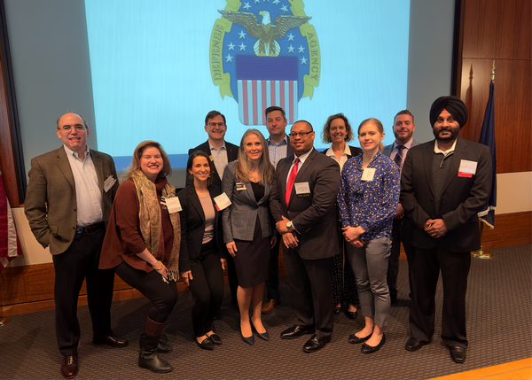 Small Business Committee volunteers and speaker pose for a photo: <br />Front Row (l-r): Adam Getz, Michele Myers, Carole Coburn, Susan Caulfield, Dwight Deneal, director of the Office of Small Business Programs for the Defense Logistics Agency, Anneli Connell and Nrip Singh<br />Back Row (l-r): Sean Caulfield, Devin Edwards, Barbara Osborne and Zak Hodges<br />