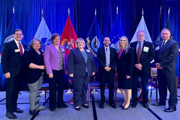 At the May Small Business Enterprise IT Day, (l-r) Sean Caulfield, chapter president; Lisa Wood, director, Procurement Technical Assistance Center, APEX Accelerator; Carlen Capenos, director, Small Business Programs, Defense Information Systems Agency (DISA); Kimberly Buehler, director, Office of Small Business Programs, U.S. Army; Farooq Mitha, director, Office of Small Business, U.S. Department of Defense; Susan Caulfield, chair, Small Business Enterprise IT Day Committee; Paul Albertson; and Scott Kiser, director, Office of Small Business Programs, U.S. Air Force, pose for a photo.
