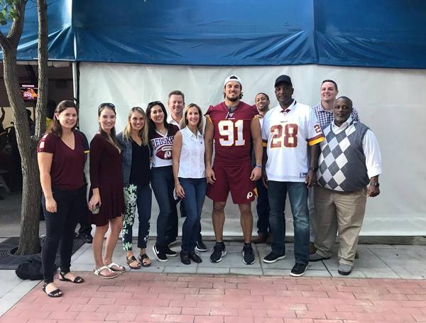 Posing for a photo at the August networking event and preseason game are (l-r) Corinne Ridderhof; Alisha Kelly; Kaitlin Bulavinetz; Therese Holland; James Evans; Tina Jordan, vice president of membership, AFCEA International; Ryan Kerrigan, Washington Redskins linebacker; Lloyd McCoy; Alvie Johnson, regional vice president, National Capital Region; Grant Jones; and Reginald Vaughn. 