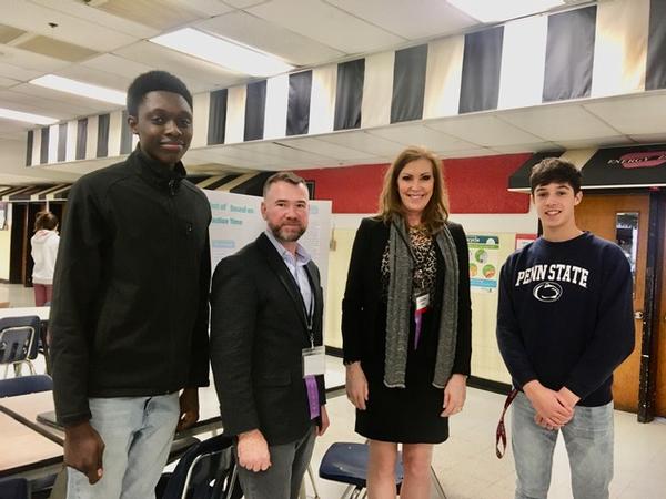 Linda Drake and Rob Landry (c) from the chapter's Education Committee and two students from the Adopt-a-School STEM program at the Herndon High School 2020 Science Fair in January pause for a photo. 