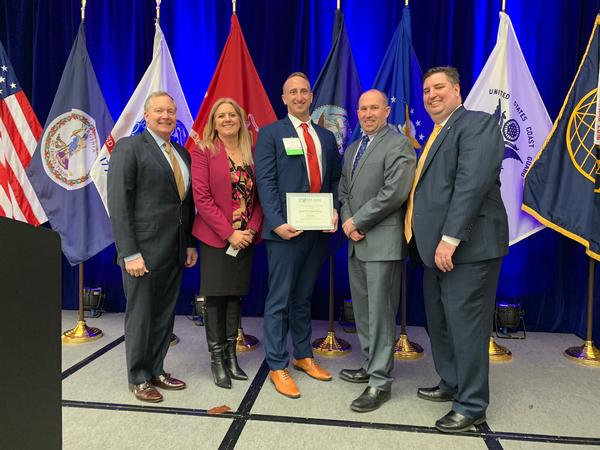 Brian Bott (c) receives Young AFCEAN of the Month Award gathers with (l-r) committee member Rear Adm. William Timme, USN (Ret.), deputy commander for Undersea Warfare for the Naval Sea Systems Command (NAVSEA); Chapter  President Tamara  Greenspan; keynote speaker Stephen Wallace, systems innovation scientist for the Emerging Technologies (EM) Directorate at DISA; and Chapter Vice President of Programs Chuck Griffith at the chapter's January meeting.     