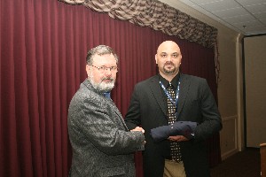 March guest speaker Albert Heitkamper (r), professor of computer science/cybersecurity at Oklahoma City Community College, receives a gift of appreciation from Marshall Guillory, program manager, Consulting Services Incorporated, and chapter executive vice president.
