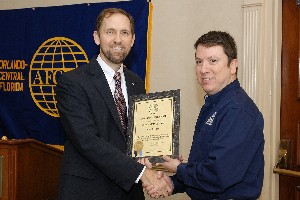 During the December meeting, Smith (l) presents a corporate membership certificate to Elvis Moreland of BEMA Services.
