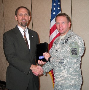 In October, Smith (l) presents a memento to Col. Mike Jones, USAR, deputy chief cyber officer, U.S. Army chief information office/G-6, in appreciation of his presentation on cyber.