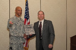 At the April luncheon, Barlow (r) presents a memento from TechNet 2010 to Col. Francisco Espaillat, USA, Project Manager Combined Arms Tactical Trainers, for his presentation.