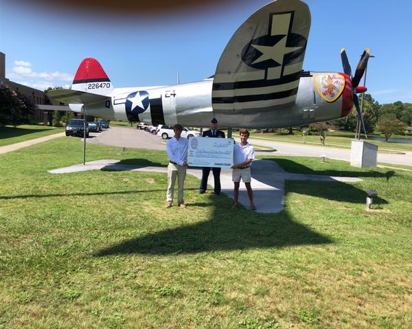 In August, Christian Hines (l) and Phillip Newman receive their AFCEA Palmetto Chapter Scholarship check for $1,000 from Lt. Col. Richard Sharpe, USAF, chapter vice president, in front of a World War II P-47 Thunderbolt at the Ninth Air Force Headquarters, Shaw Air Force Base, South Carolina. 
