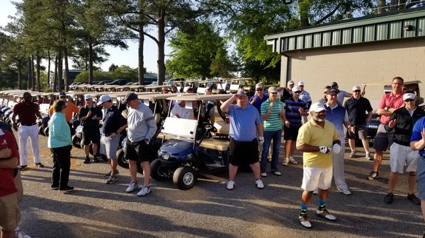 Eleven teams listen as Eric Wilson, golf course manager, and John DeBerry, U.S. Air Forces Central Command A-6, chief of plans and requirements, give the rules of engagement for the shotgun start of the April fundraiser tournament.