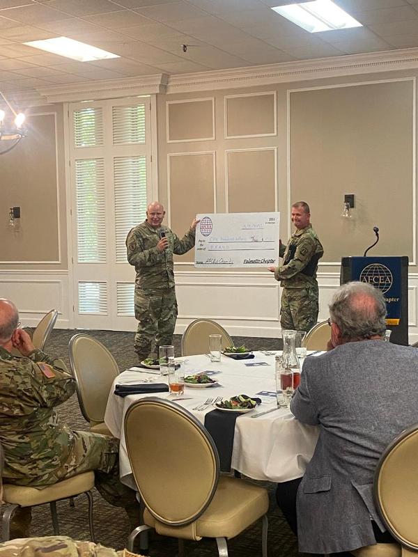 In June, Col. Gary Cornn, USAF, director, U.S. Air Force Central, A-6, presents Brig. Gen. Robert Powell Jr., USAR, the U.S. Army Central G-6, with a check for a donation to the charity of Gen. Powell's choosing.