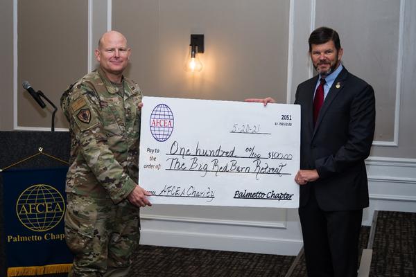 In May, Col. Gary Cornn, USAF, chapter president (l), presents Gen. McCaffrey with a check for $100 to his favorite charity, The Big Red Barn Retreat. 