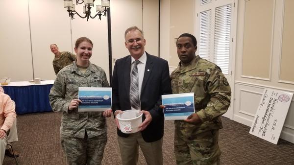 DeBerry (c) awards two one-year AFCEA memberships at the April luncheon to Staff Sgt. Dereth Worrell, USAF (l), and Tech. Sgt. Joseph McMillan, USAF, both from AFCENT's 609th Air Operations Center. Col. Mueller photo-bombs the group. 