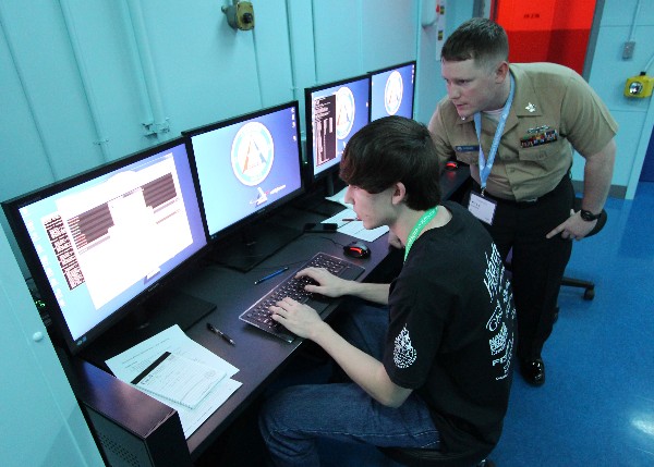 Information Systems Technician 1st Class Kyle Gosser, USN, instructor at the Center for Information Dominance Unit Corry Station, mentors a local high school student participating in the inaugural Cyberthon competition held at the National Flight Academy on board Naval Air Station Pensacola during January. The Cyberthon competition is designed to test student teams on their abilities to use the computer skills they learned in their classrooms to defend and defeat cyber attacks on websites.