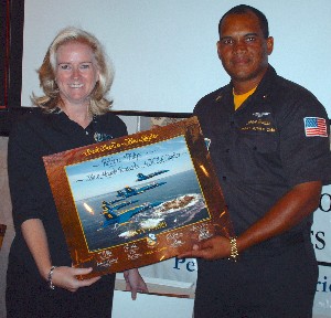 Robyn Philips, president of the Blue Angels Pensacola chapter, accepts a commemorative autographed 60th anniversary lithograph from guest speaker MCC (AW/SW) Victor Brabble, Asst. Public Affairs Officer for the U.S. Navy Flight Demonstration Squadron.
