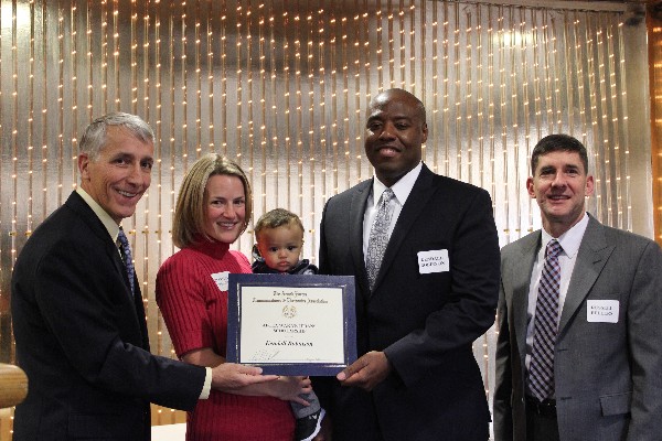 Phil Platt (l), chapter president, presents a $2,500 AFCEA Scholarship to Kendall Robinson (2nd from r) who is accompanied on stage by his wife Helen, his child Emmitt and Russ Fellers, chapter vice president for education.