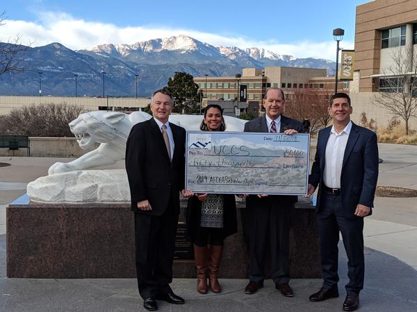 In December, Rod Pohlmann, chair, chapter investment committee (l), and Russ Fellers, chapter vice president for education (far r), present a check for $50,000 for STEM-related scholarships to Zuleika Johnson and Martin Wood, both of the University of Colorado Colorado Springs.