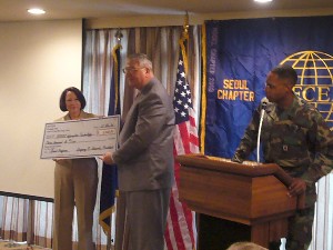 Seoul chapter president Col. Greg Edwards, USAF, and Adm. Brown present an information technology program grant to the Department of Defense Dependents Schools-Korea's district superintendent Charles Toth (c) at the November meeting.