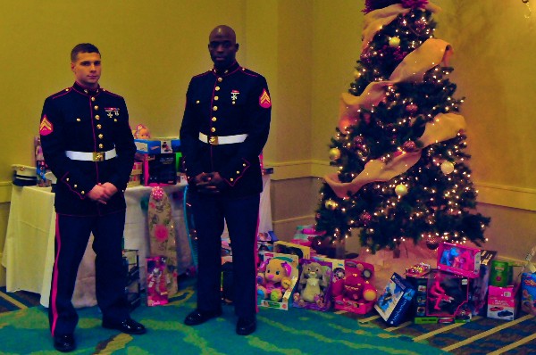 Cpl. Curtis Smiley, USMCR, and Cpl. Dustin Owens, USMC, accept the Toys for Tots donations on behalf of the United States Marine Corps during the December social.