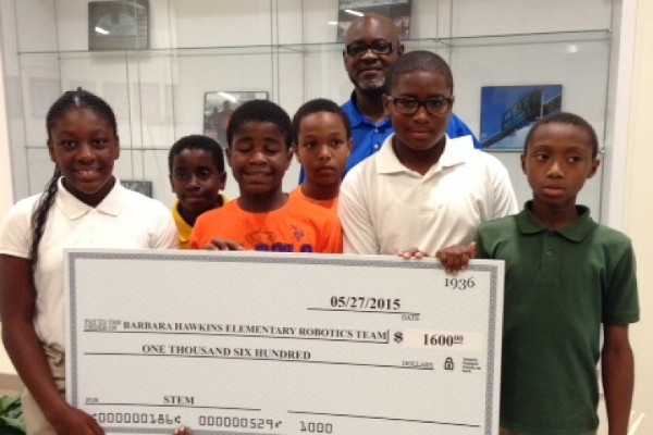 Walter Lewis, Exeter Information Technology Services and chapter first vice president (c), presents a check in May to fifth-grade students at Barbara Hawkins Elementary in Miami Gardens, Florida, to support its robotics program. 