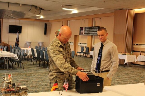 A student describes his solar battery charger project to Col. Boenisch (l) at the May scholarship event. 