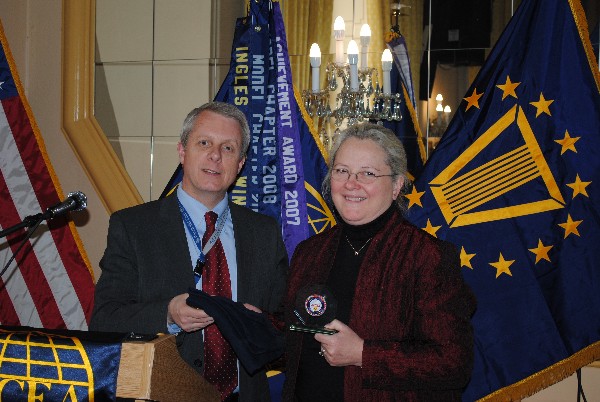 Roger Carpenter, chapter president, presents Moran with a chapter shirt and coin at the April luncheon.