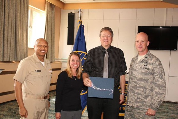 Capt. Ramberto Torruella, USN, chapter president (l), with guest speaker Col. Boenisch (r), presents $1,000 for future STEM studies and programs to Stephanie Payne and Brad Rehwaldt (2nd from r), both teachers at Patch High School.