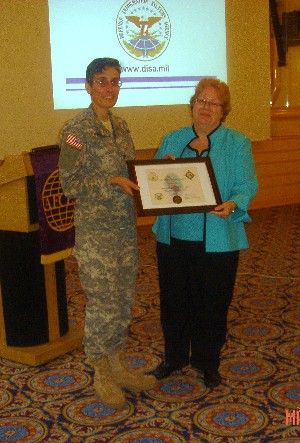 During the March meeting, Kathleen Miller (r), director for procurement, Defense Information Systems Agency, accepts a plaque from Col. Michelle Fraley, USA, chapter president, for her continued support of the chapter.