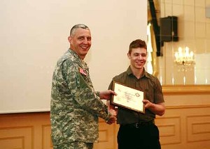 Col. Curry (l) presents Christopher Noelting (r) from the International School of Stuttgart with a $3,000 scholarship award in U.S. savings bonds at the June scholarship luncheon.  Noelting was one of the four scholarship winners recognized for their technology presentations.  A total of $10,000 in U.S. savings bonds were given to the winning students from the Stuttgart area.
