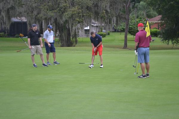 Participants watch a golfer on the Hole 4 putting green at the November tournament.