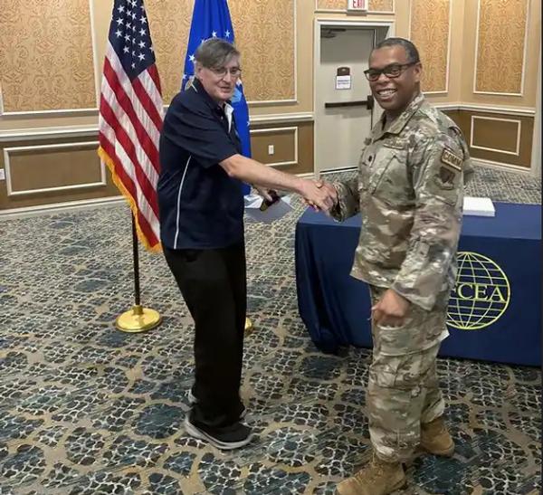 Sam Moore, chapter program director, and Lt. Col Justin Handley, USAF, outgoing chapter president, shake hands at the July luncheon.