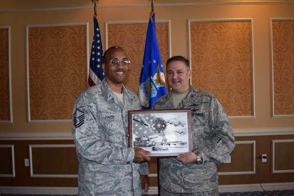 At the May luncheon, Col. Folks (r) presents a plaque to Master Sgt. Clyde Hardy, USAF, of the 10th Intelligence Squadron, who was selected the AFCEAN of the Month for April.