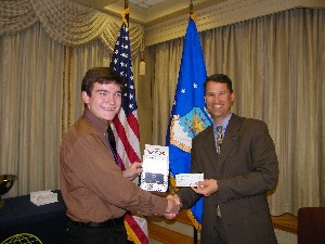 In March, Marion (r) presents Joseph Miller of the Twisted Botz Robotics Team with a check for $1,000 to support the team as they prepare to participate in the upcoming Robotics World Championship.