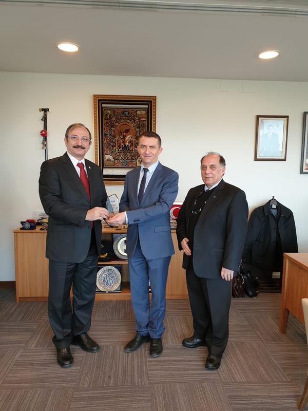 Kamil Zafer Selcuk, chapter president (far l), and Zafer Betoner, chapter vice president (far r), present the visiting plaque to Neset Ertas, Command Control and Information Systems Projects Group Manager, as a token of appreciation during their March visit.