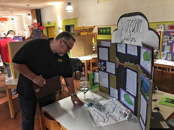 Guest judge Rink reviews a topological map outlining the affected areas of a volcanic eruption at the December STEMposium.