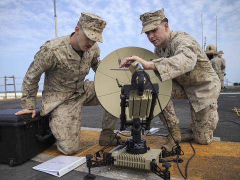 U.S. Marine Corporals Josrdan Hoskison (l) and Jacob Jusczak, both data system administrators with the 22nd Marine Expeditionary Unit, set up a Multi-Mission Terminal satellite on the flight deck of the Wasp-class amphibious assault ship USS Kearsarge (LHD-3). The satellite enables secure access to Internet Protocol broadband networks and the establishment of command post communications from any location. Credit: Tawanya Norwood, 22nd Marine Expeditionary Unit