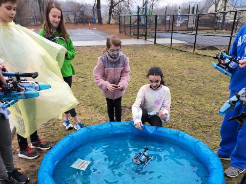 Students learn about air-powered boats using a kiddie pool.