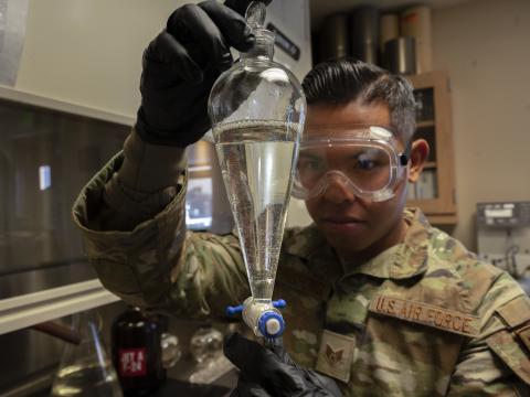 A U.S. Air Force staff sergeant inspects a flask of jet fuel as part of quality control measures. Reducing fuel consumption is a major element of Air Force climate change efforts. Credit: U.S. Air Force