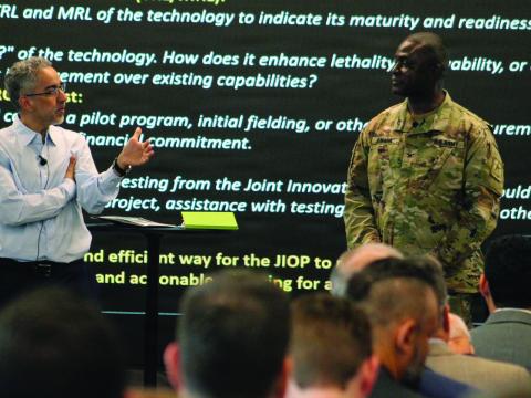 The U.S. Army Capability Program Executive Simulation, Training, Test and Threat’s chief technology officer, Marwane Bahbaz (l), speaks to Col. Peter Amara, assistant director to the deputy assistant secretary of the Army for Data, Engineering and Software and industry representatives during a Technical Exchange/Industry Day in March at the Central Florida Tech Grove in Orlando, Florida. U.S. Army photo by Donnie Ryan