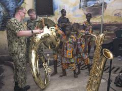 A Navy musician shows his tuba to children during a U.S. Naval Forces Europe and Africa Band concert in Ghana, as part of the diplomacy and cooperation Western armed forces are involved in throughout the continent. Photo By: Navy Petty Officer 2nd Class Trey Fowler