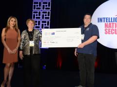 Niloo Norton, chair of AFCEA’s EPIC Committee (l), and Ann Carbonell, director of the Commercial Innovation Center of Riverside Research (c), present a $13,000 check to David Vigna, founder of Frost Mountain and winner of EPIC Challenge 2022, at the Intelligence & National Security Summit. 
