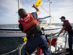 A Coast Guardsman throws a rope across to a stranded sailor during a rescue in the Gulf of Mexico. Photo By: U.S. Air Force photo, 2nd Lt. Karissa Rodriguez.