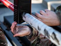 A Civil Engineer Squadron electrical power production journeyman inserts a metal wire into an encasing for a ground automobile retractable barrier net, at Dover Air Force Base, Delaware. Credit: Senior Airman Marco A. Gomez, U.S. Air Force