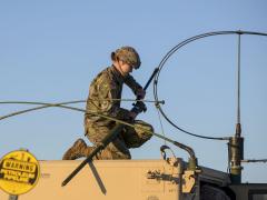 A soldier attaches long-range radio equipment to a Humvee at Fort Greely, Alaska, October 2020. Photo by Air Force Senior Airman Beaux Hebert