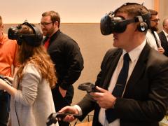 Two engineers fly around the topside of Navy ships via virtual reality while a third explores the interior of an amphibious transport dock ship’s pilot house. Photo credit: U.S. Navy.