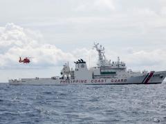 U.S. Coast Guardsmen, assigned to the U.S. Coast Guard Cutter Waesche (WMSL-751), pilot a U.S. Coast Guard MH-65E helicopter over the flight deck of the Philippine Coast Guard Vessel Melchora Aquino (MRRV-9702) during a bilateral U.S.-Philippine search and rescue exercise in the South China Sea on July 16, 2024. To assist the “ever-expanding” missions in the Indo-Pacific region, NGA is testing commercial solutions to help track illicit maritime activity. Credit: USMC photo by Cpl. Elijah Murphy.
