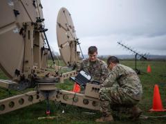 U.S. Air Force Airman 1st Class Ryan Smith (l) and Airman 1st Class Yekun Yang, both 1st Combat Communications Squadron radio frequency transmissions system technicians, check cable connections on a satellite dish during the HEAVY RAIN 23 exercise, at Grostenquin, France, on November 16, 2023. The squadron is part of the 435th Communications Operations Group, based in Ramstein Germany, which is undergoing an evolution to provide expeditionary communications in a contested environment.