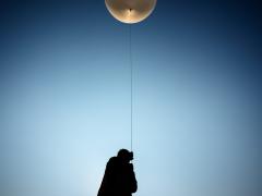 Summer Czarnowski, a geosciences intern at Sandia National Laboratories, holds a line tethered between a scientific payload and a weather balloon prior to launch at Moriarty Airport in New Mexico in July. Credit: Craig Fritz