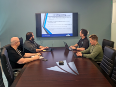 Members of IntelliGenesis' Cybersecurity Maturity Model Certification (CMMC) team discuss the process of meeting the CMMC requirements. Credit: IntelliGenesis photo by Laura Hildebrand