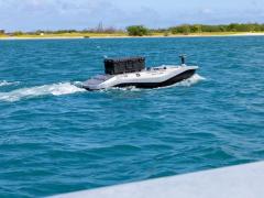  An unmanned surface vessel moves out to sea from Sand Island near Honolulu to deliver parts for a 3D printer aboard the Wasp-class amphibious assault ship USS Essex (LHD-2) during Exercise Rim of the Pacific 2026, July 7, 2026. Although there is no human operator aboard such a vessel, there is a human footprint—and often a very large one—needed to operate and maintain an “unmanned system,” the author says. Credit: U.S. Navy photo by Mass Communications Specialist 3rd Class Charles Harbour