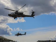Two U.S. Army AH-64E Apache Guardian attack helicopters assigned to the 1st Cavalry Division fly over an observation area during a multinational live-fire exercise as part of DEFENDER-Europe 22 at Mielno Range in Drawsko Pomorskie, Poland on May 27. Manufacturer Elbit Systems of America is offering a new dual eye visor helmet system for helicopter pilots that incorporates multiple layers of real-time and historical data from multiple sensors. Credit: Department of Defense